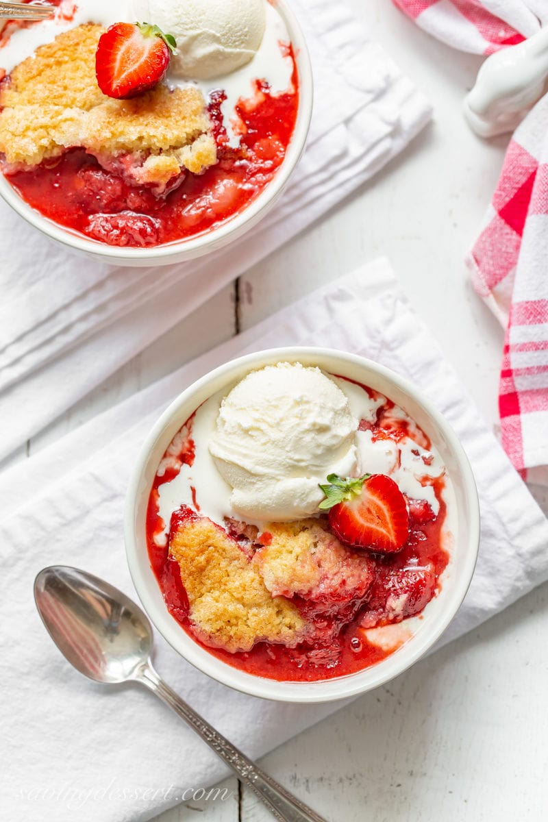 Two bowls of juicy strawberry cobbler topped with vanilla ice cream