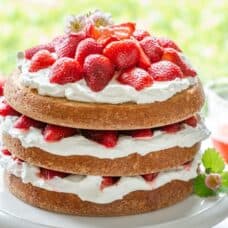 A three layer cake with whipped cream and fresh strawberries between each layer.