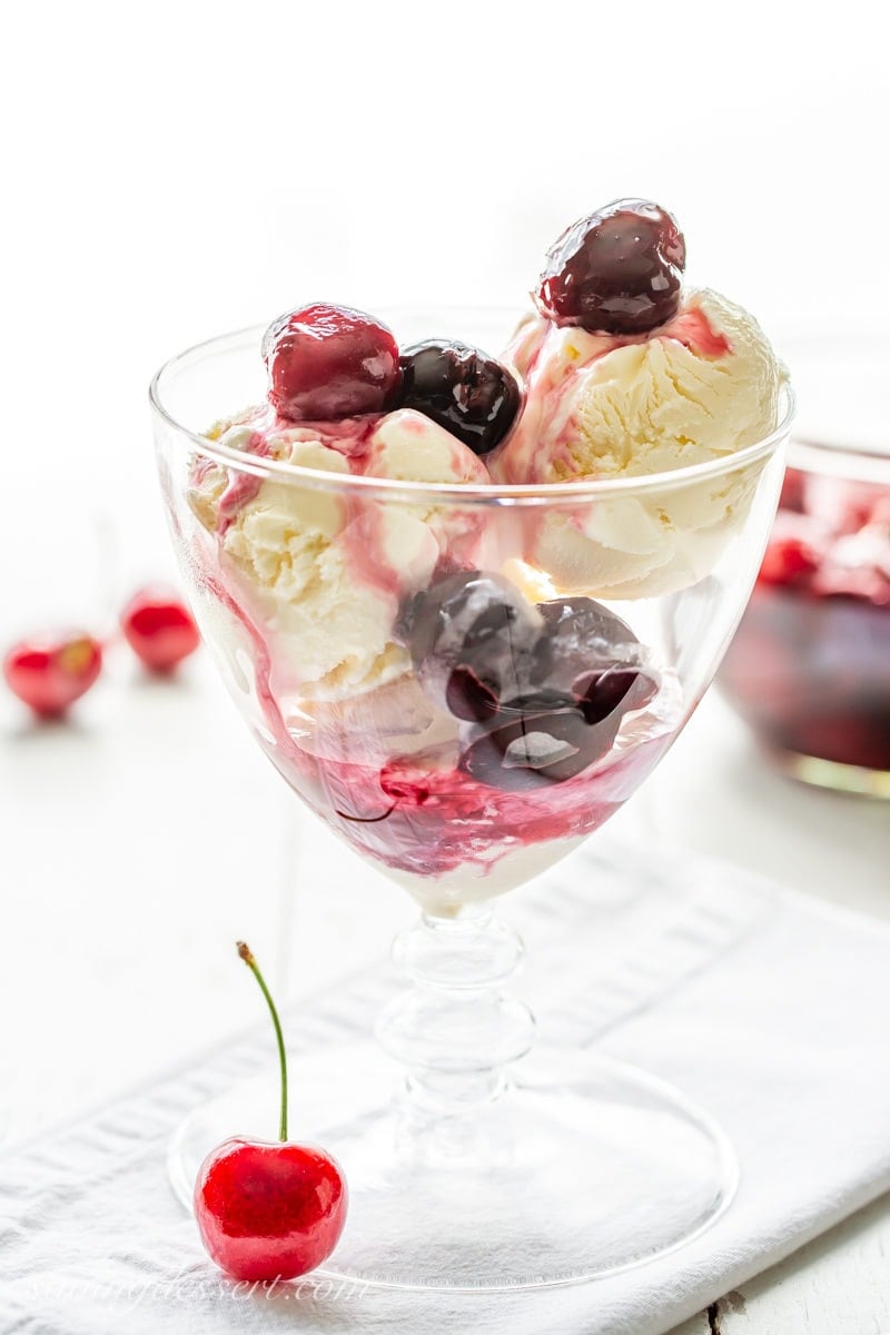 Scoops of vanilla ice cream in a glass topped with Cherries Jubilee