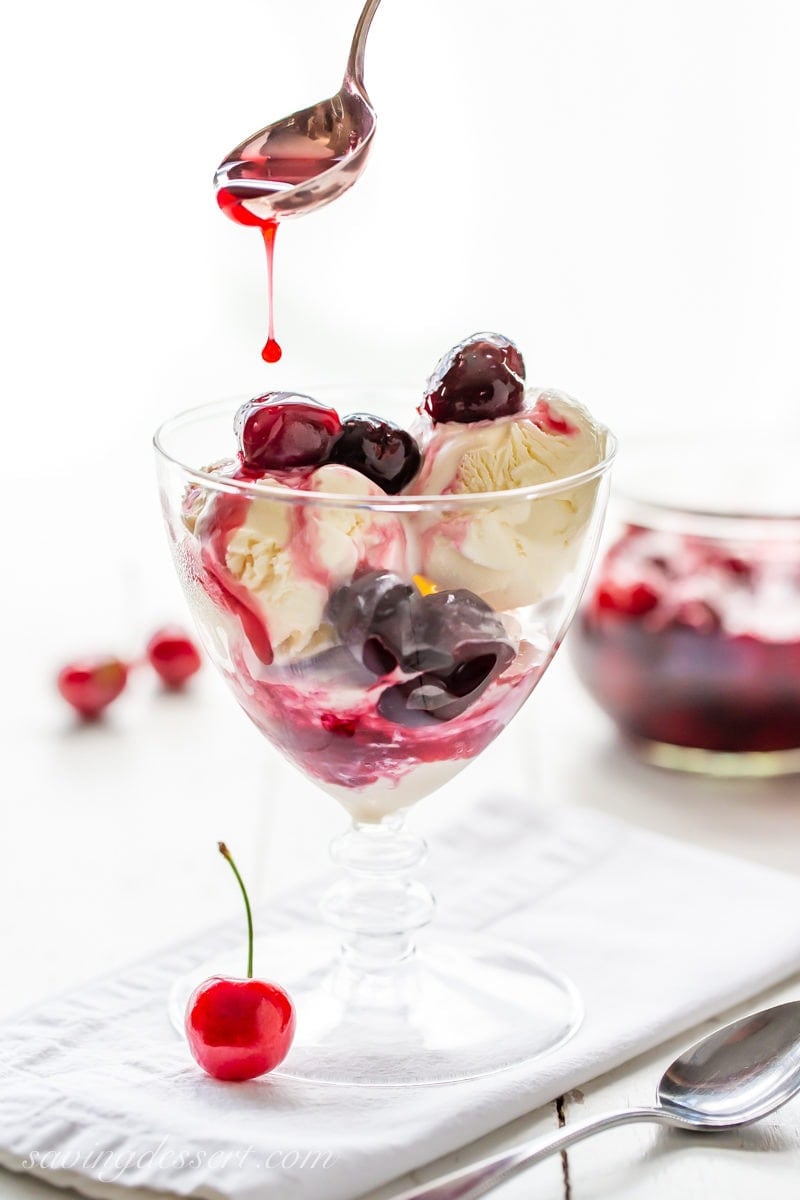 A pretty dessert glass with vanilla ice cream topped with warm Cherries Jubilee sauce