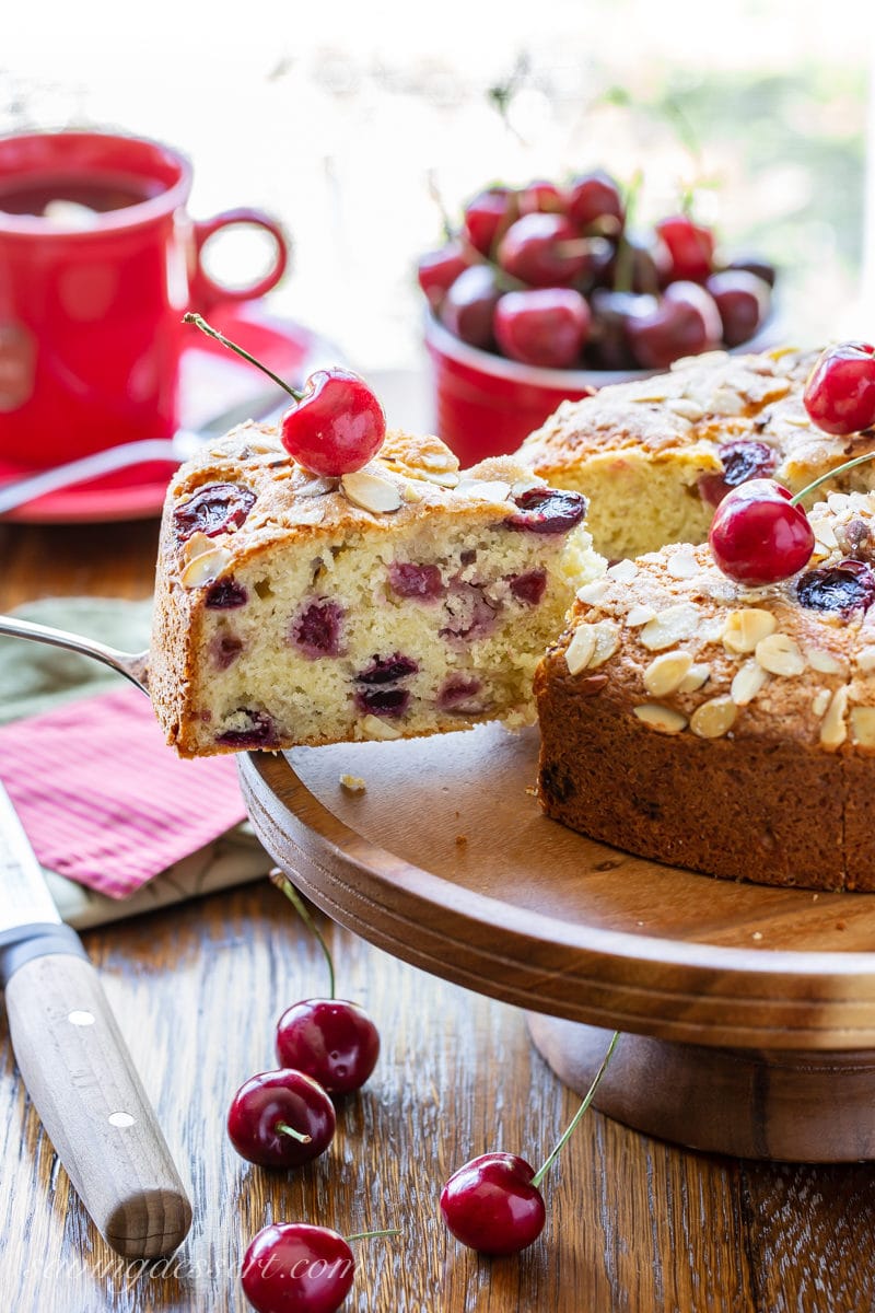 A sliced cherry breakfast cake with almonds and fresh cherries on top