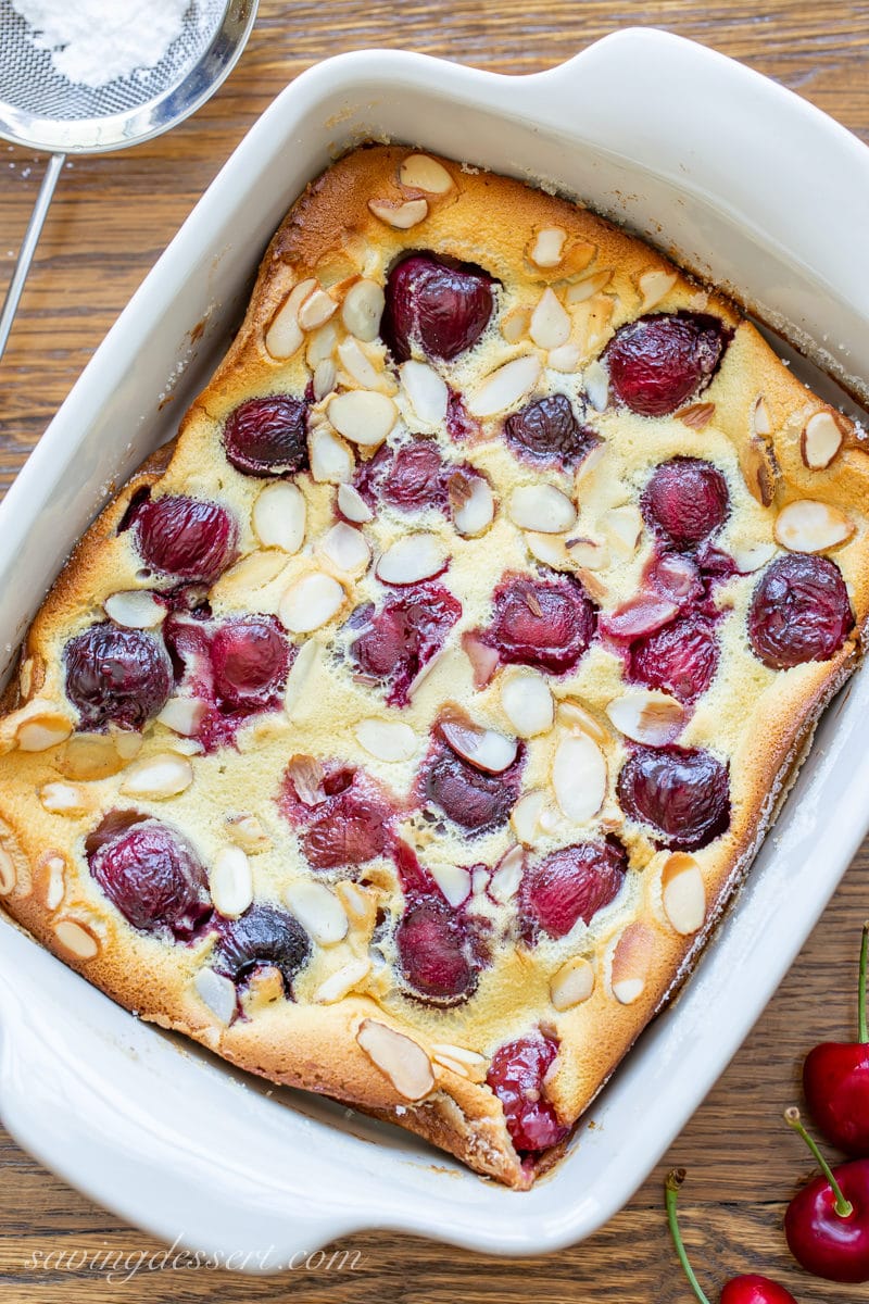 A small casserole dish with Cherry Clafoutis topped with sliced almonds