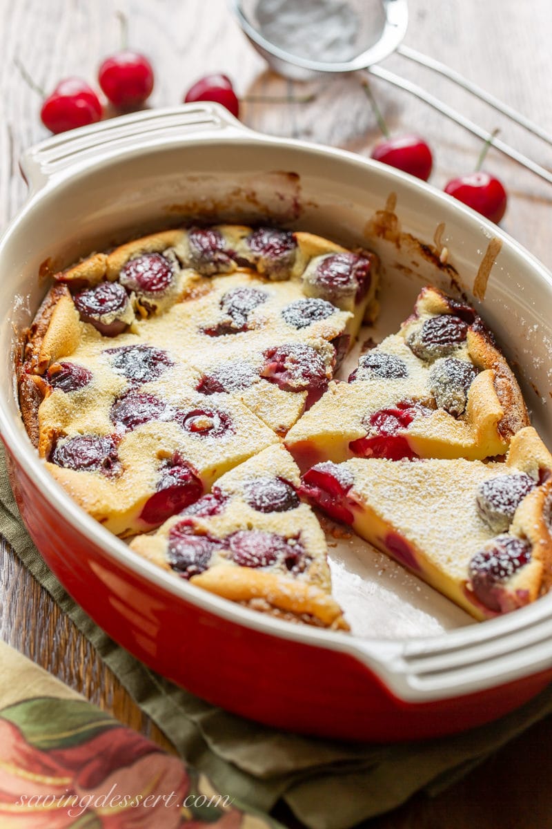 Casserole dish with sliced wedges of Cherry Clafoutis dusted with powdered sugar