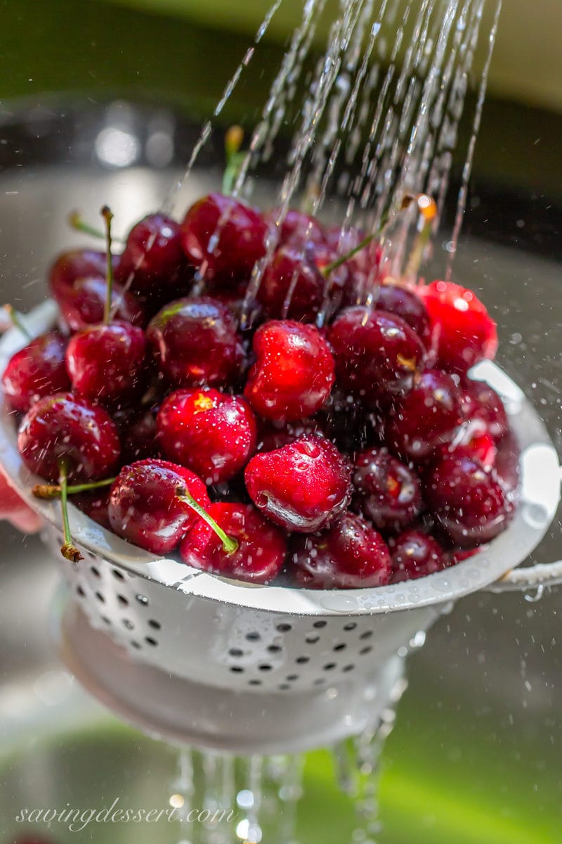 A bowl of fresh cherries washed in a cold stream of water