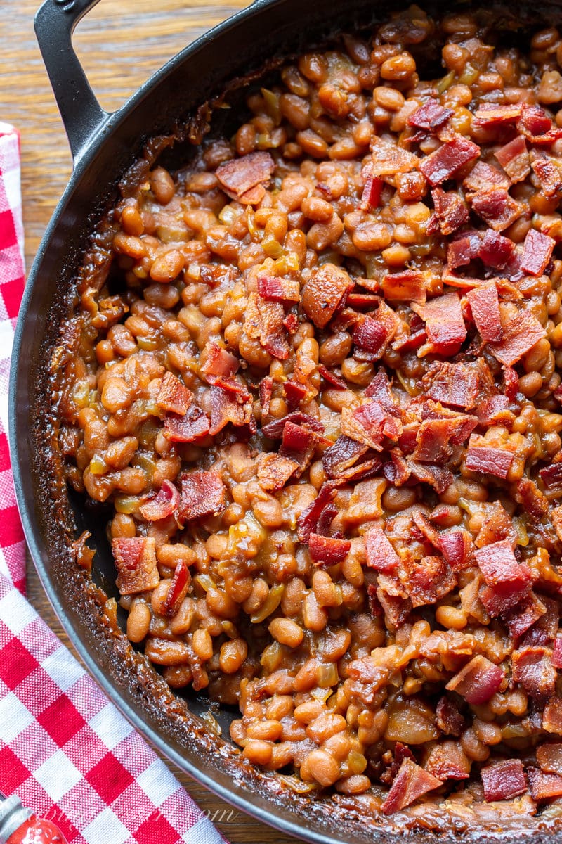 A skillet with oven baked beans topped with crumbled bacon
