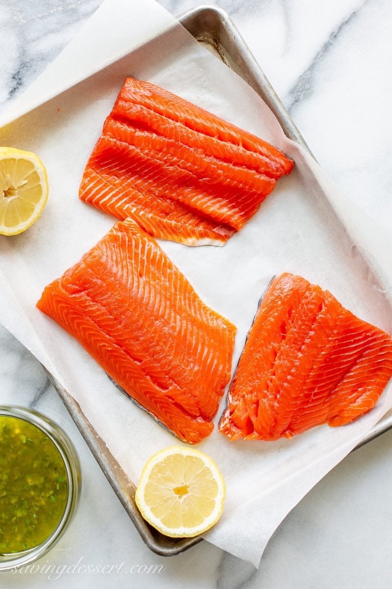 A tray with fresh, pink salmon fillets and lemon halves