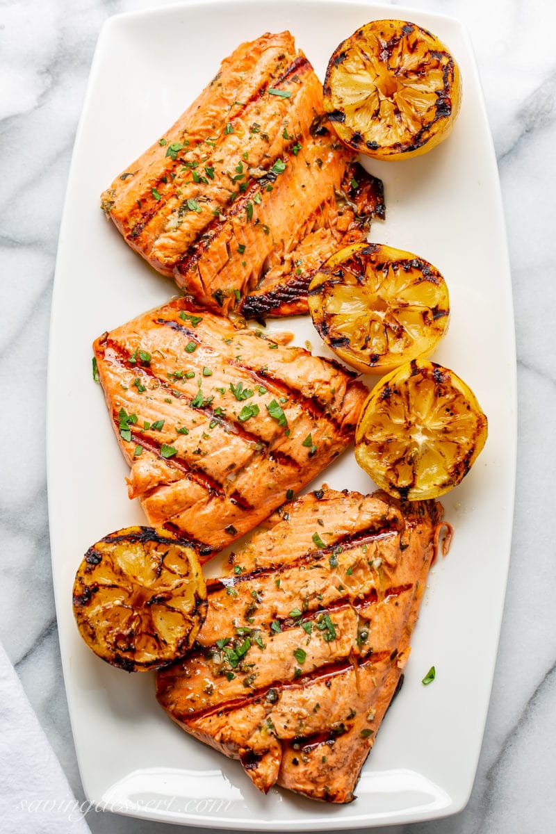 A platter with grilled salmon fillets and grilled lemons