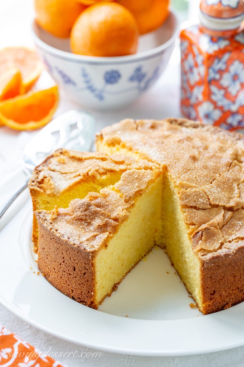 A sliced orange olive oil cake on a platter with sliced oranges