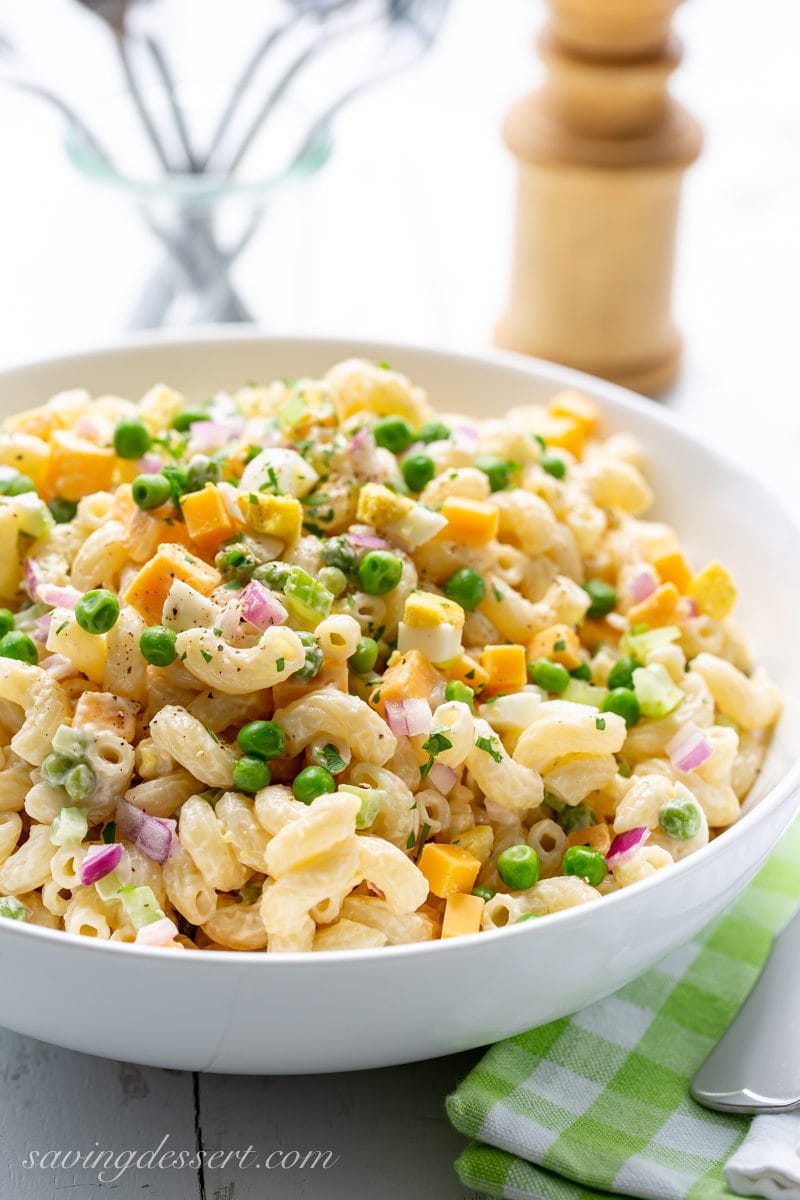 A bowl of macaroni salad with peas, cheese and red onion