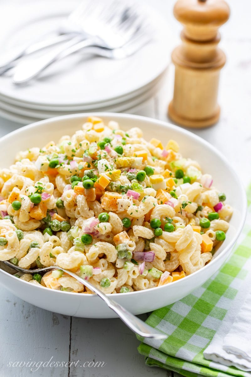 A bowl of macaroni salad with peach, red onion and cheddar cheese chunks