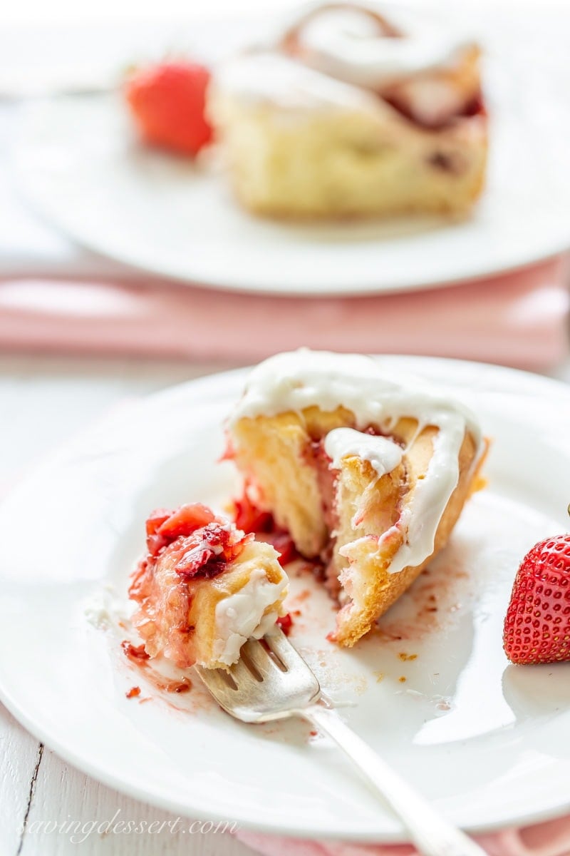 A strawberry sweet roll filled with strawberry jam and fresh berries topped with cream cheese icing