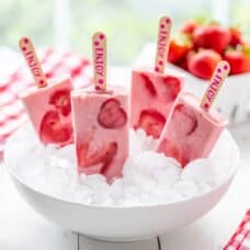 A bowl of ice with strawberry popsicles sticking up
