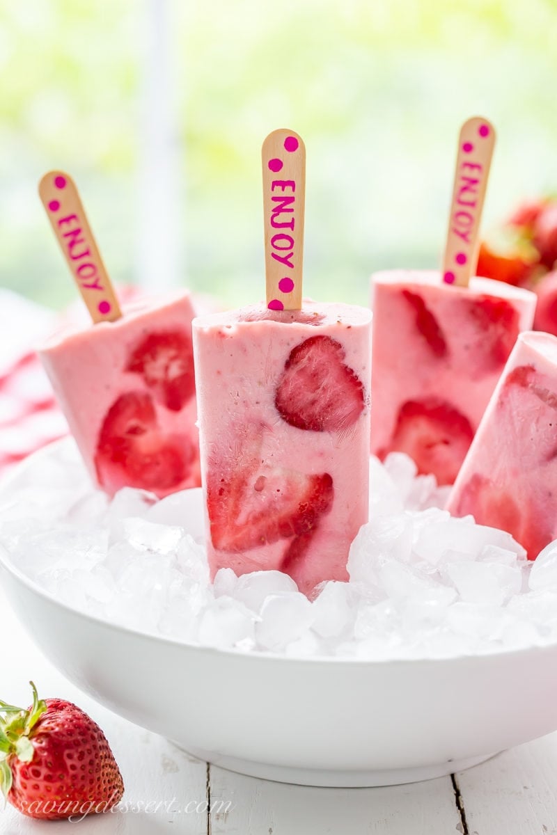 A bowl of ice and fresh strawberry yogurt popsicles