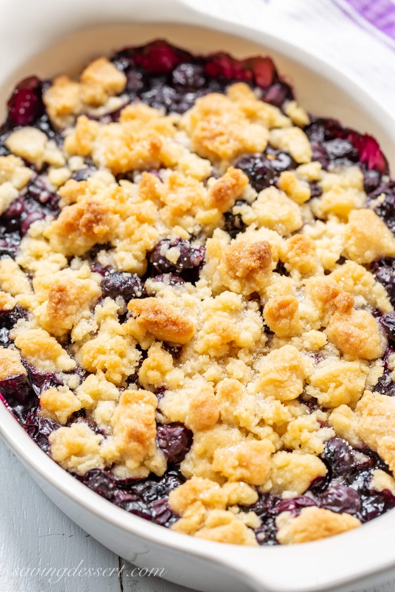 A casserole dish with a hot blueberry crisp with a buttery crumble topping