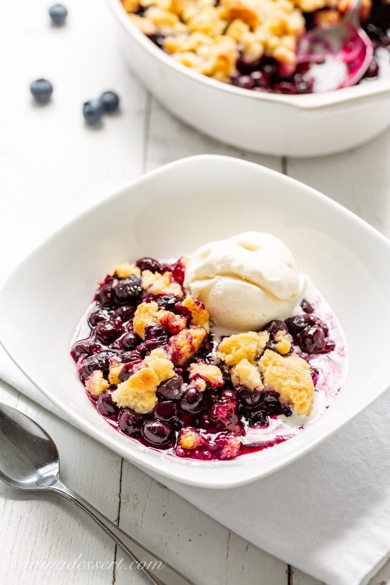 A bowl of blueberry crisp topped with a scoop of vanilla ice cream