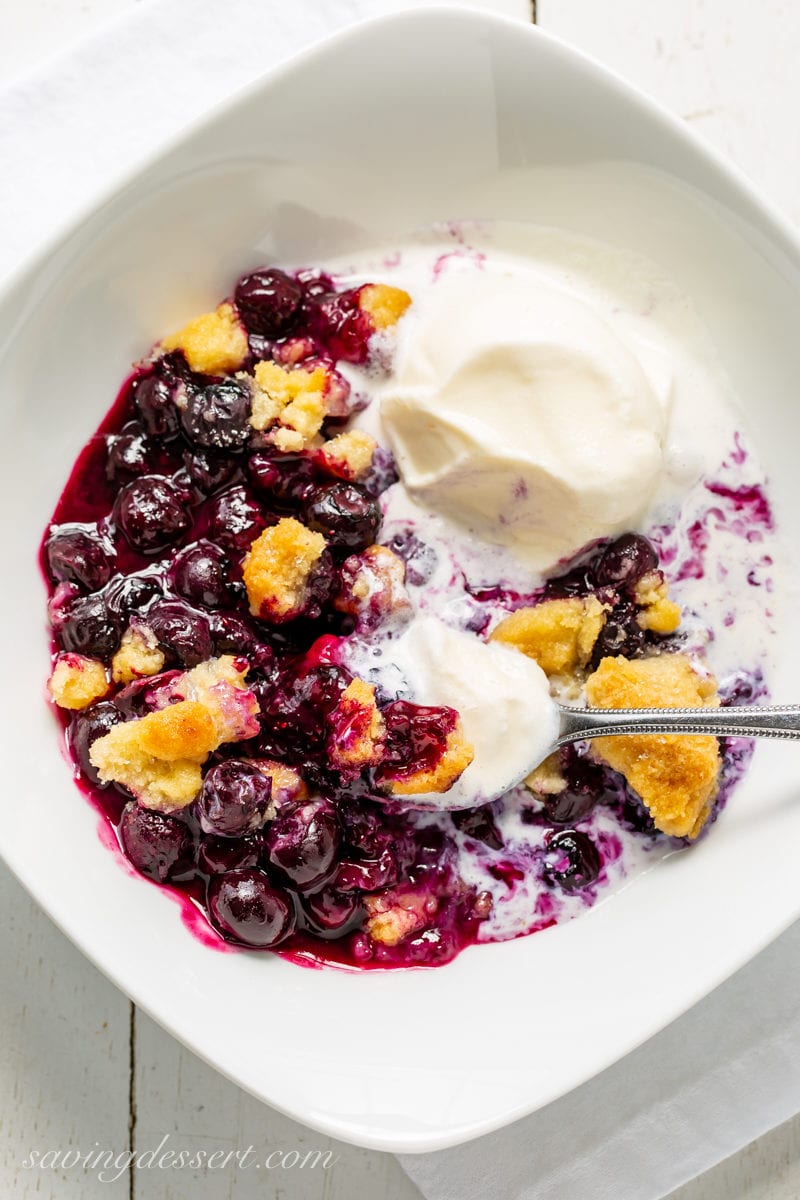 A bowl filled with warm blueberry crisp topped with melting vanilla ice cream