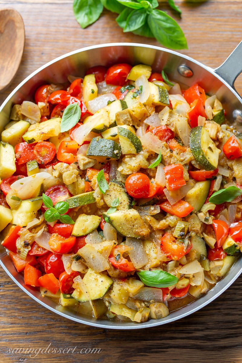 A skillet filled with eggplant caponata with zucchini, onions, tomatoes and red bell pepper