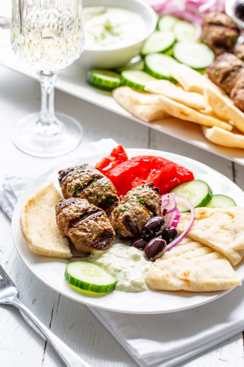 A small plate (meze) with kebabs, cucumber, tomatoes, onion, olives, cucumber-yogurt sauce and pita wedges
