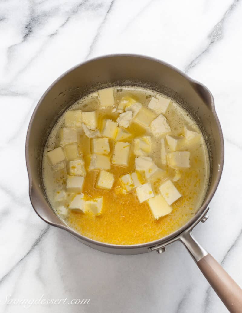 A saucepan filled with butter squares, lemon juice and sugar.