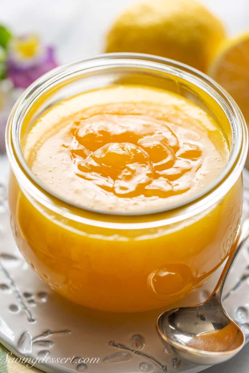 Lemon Curd in a wide mouth jar with a spoon.