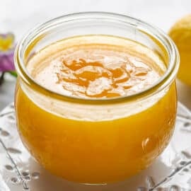 A jar of lemon curd on a plate.