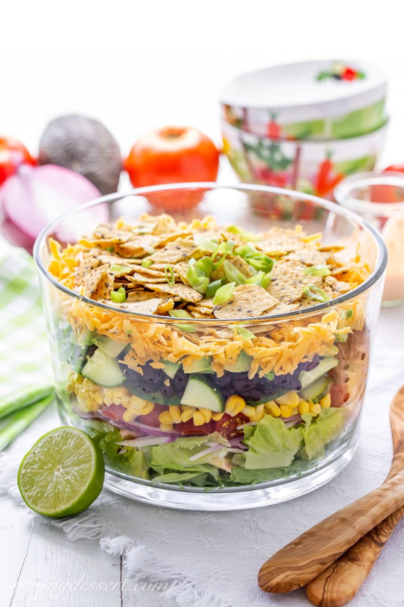 A trifle bowl with a layered Mexican Salad with chips on top