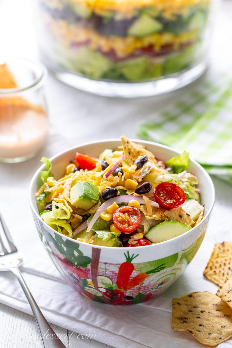 A bowl of Mexican Layered Salad with tomatoes, avocado chunks, cucumber and sliced red onion