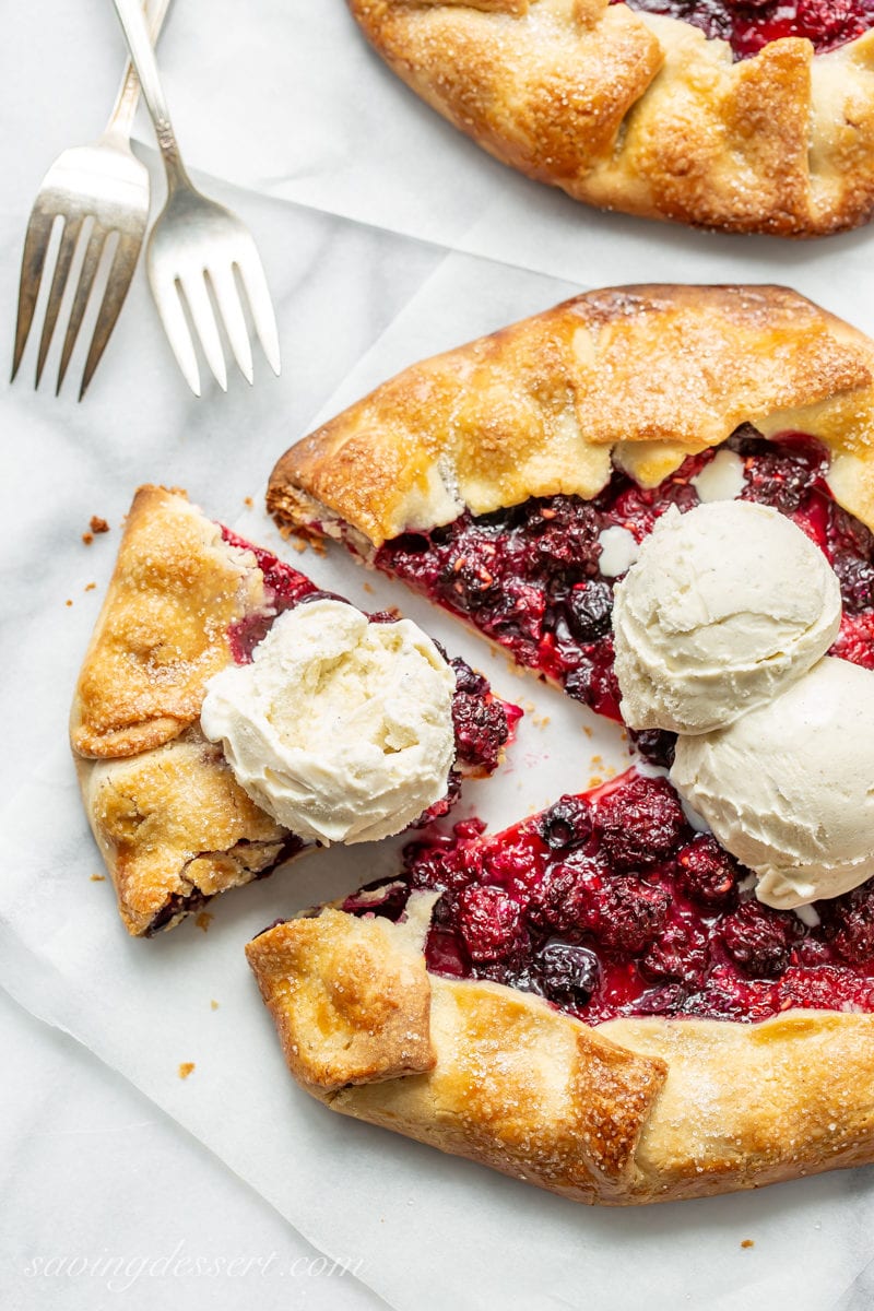 A sliced mixed berry crostata topped with scoops of vanilla bean ice cream