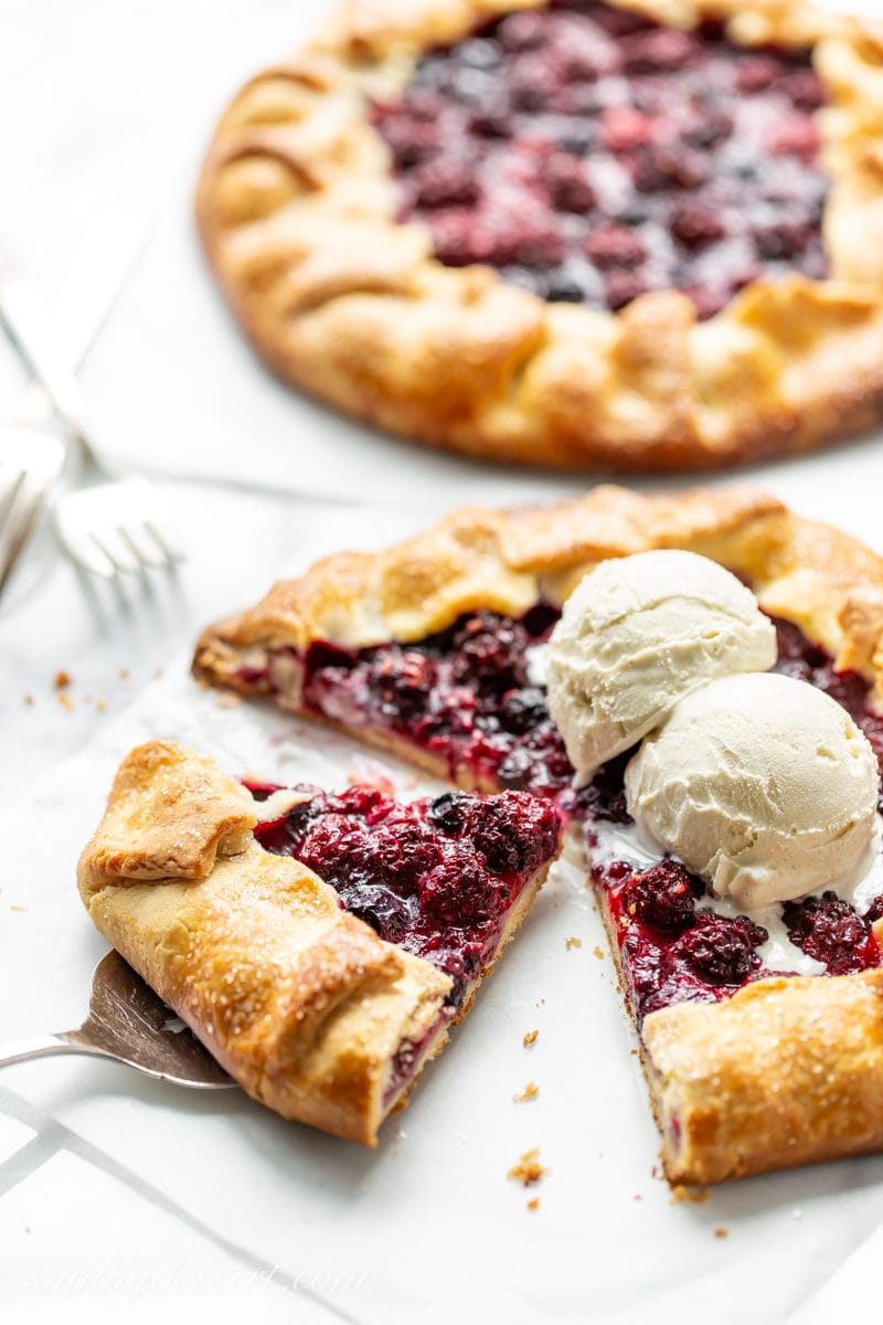 A sliced mixed berry crostata topped with vanilla bean ice cream