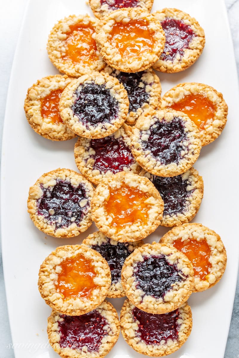A plate filled with oatmeal jammys with apricot, blueberry and raspberry jam