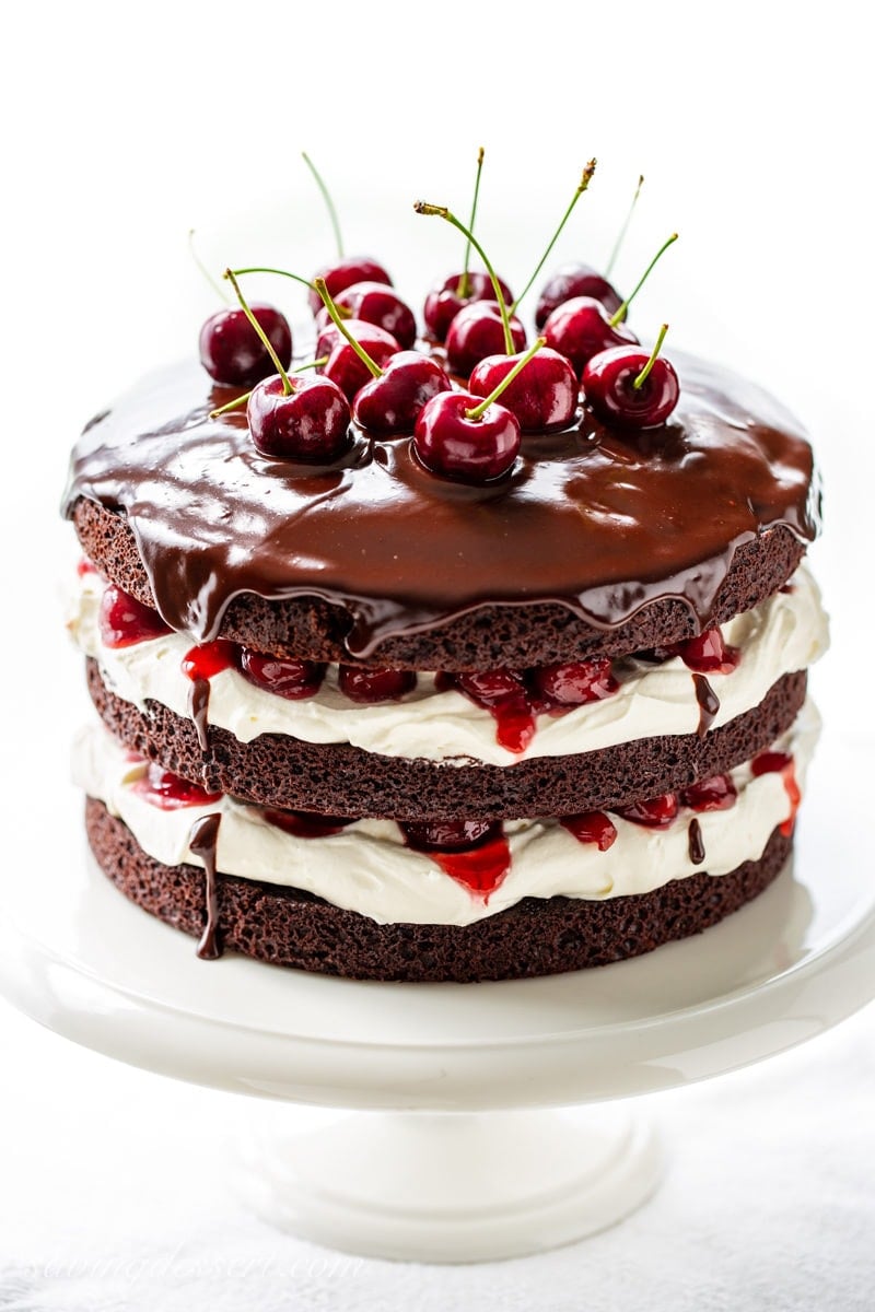 A three layer Black Forest Cake garnished with chocolate ganache and fresh cherries