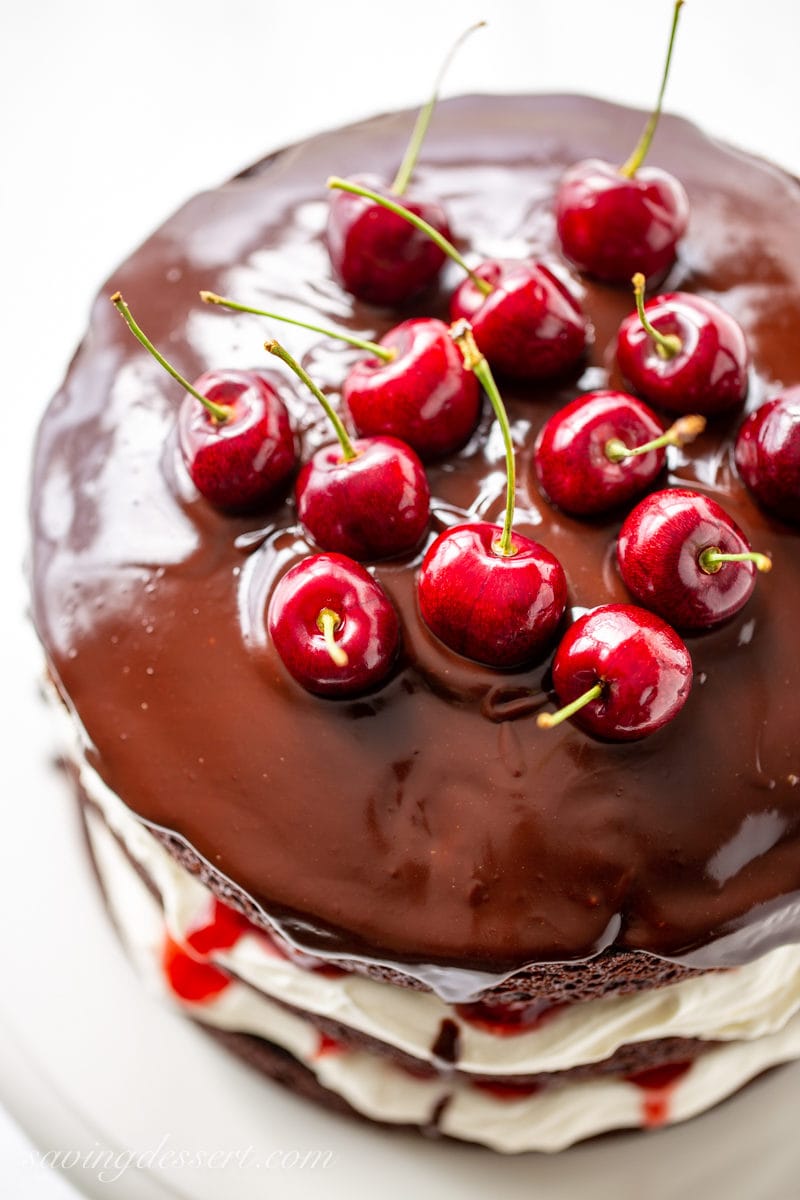 A closeup of fresh cherries sitting in a chocolate ganache on top of a Black Forest Cake