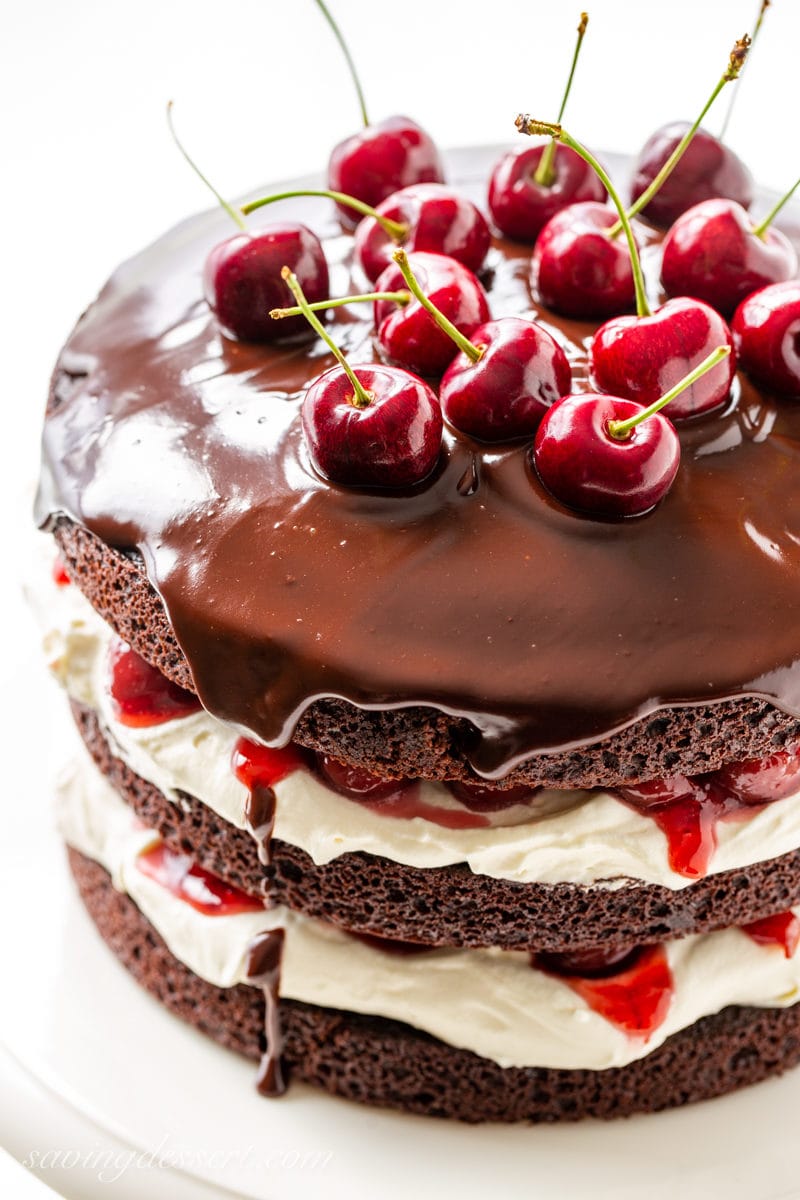 A Black Forest Cake topped with a silky chocolate ganache and fresh sour cherries