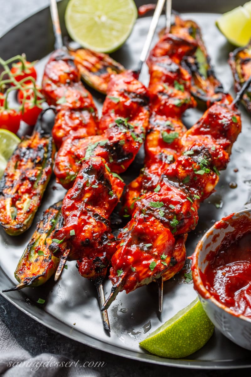 Grilled chicken skewers with charred jalapeño peppers and lime wedges
