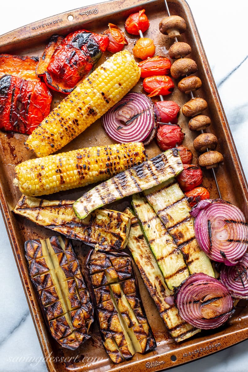 A tray of grilled corn, onion, tomatoes, mushrooms, peppers, squash and eggplant