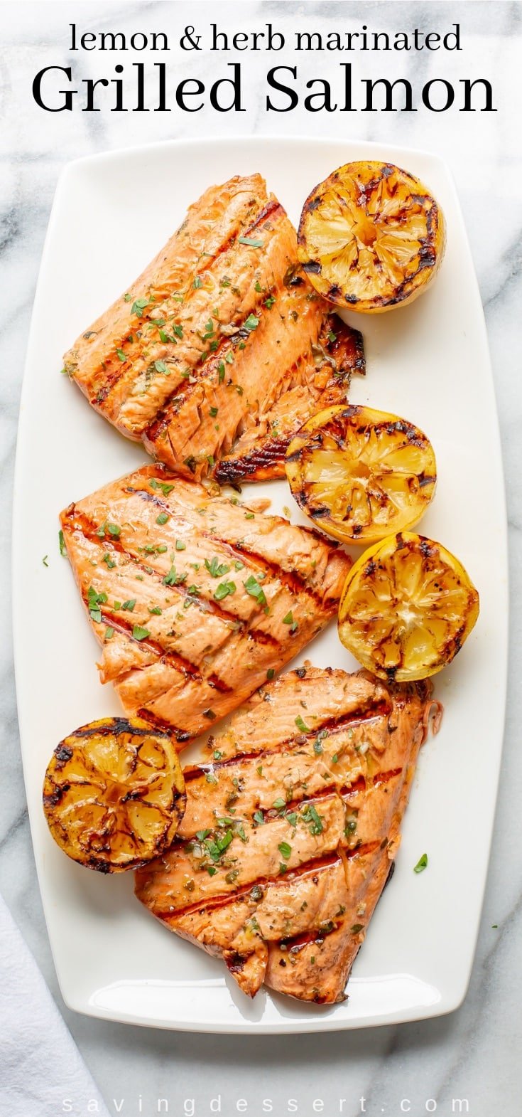 A platter with grilled salmon and lemons garnished with fresh parsley