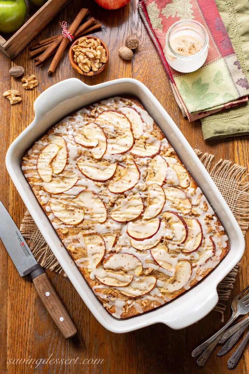 An apple sheet cake covered with sliced apples, drizzled with a simple icing and a sprinkle of cinnamon