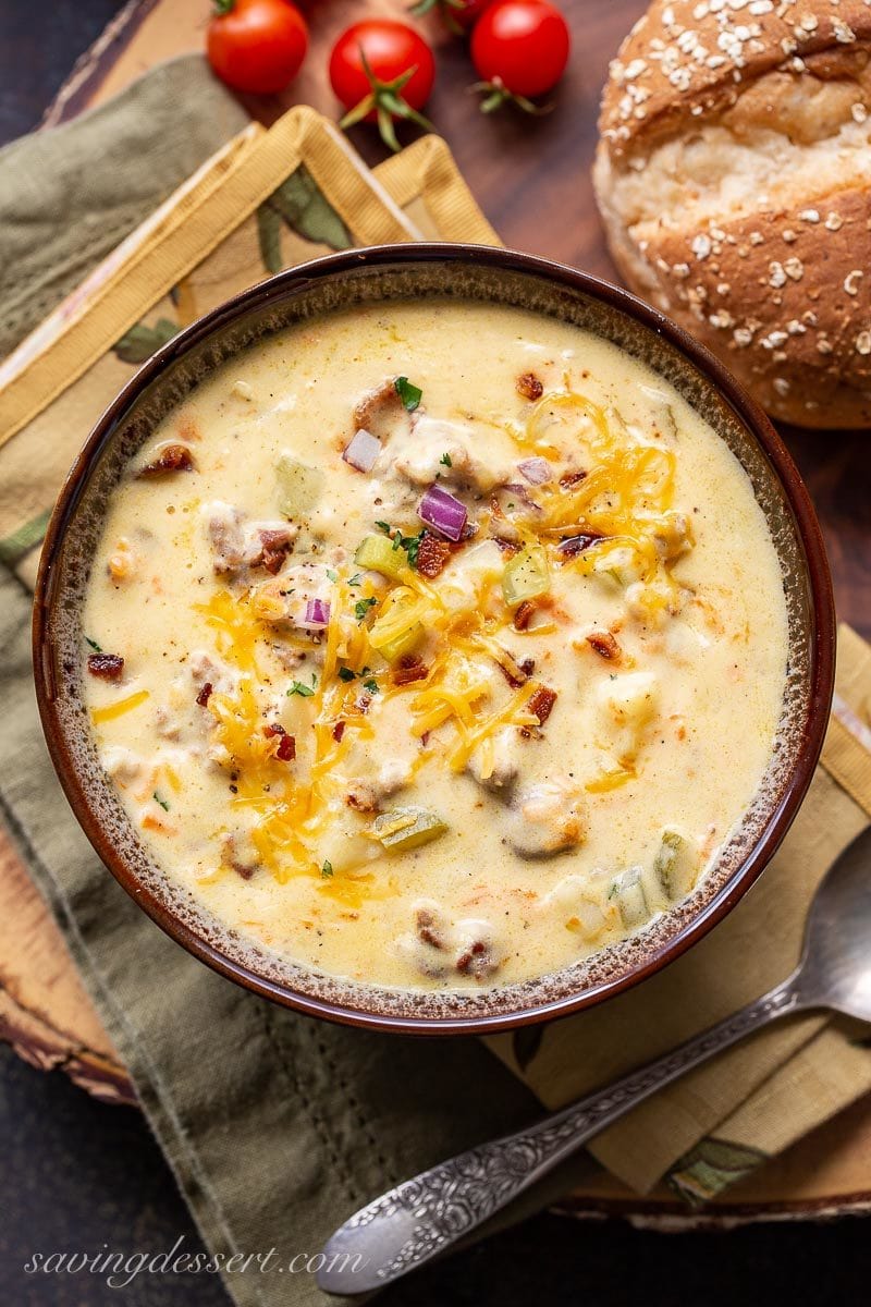 A bowl of creamy cheeseburger soup garnished with bacon, onion and extra cheese
