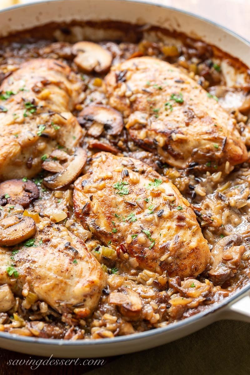 A skillet with chicken breasts, mushrooms and wild rice casserole