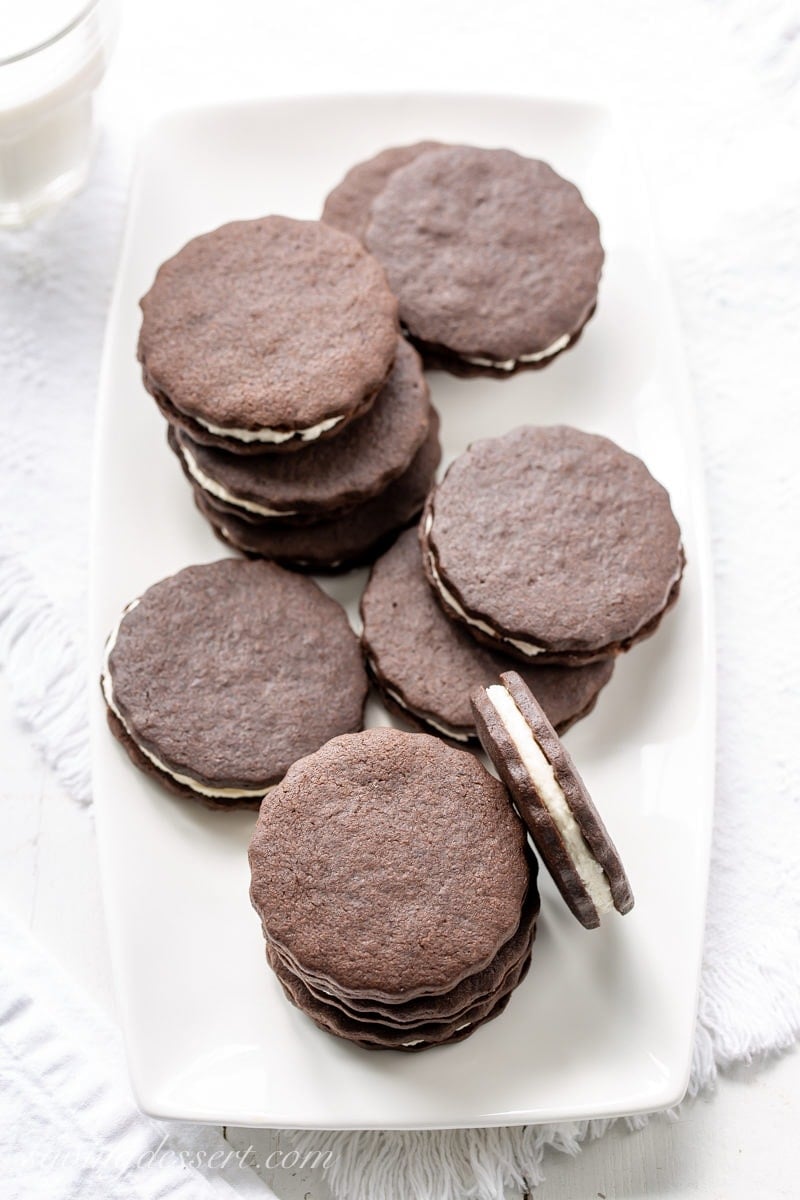A plate of round chocolate sugar cookies sandwiched with vanilla cream frosting