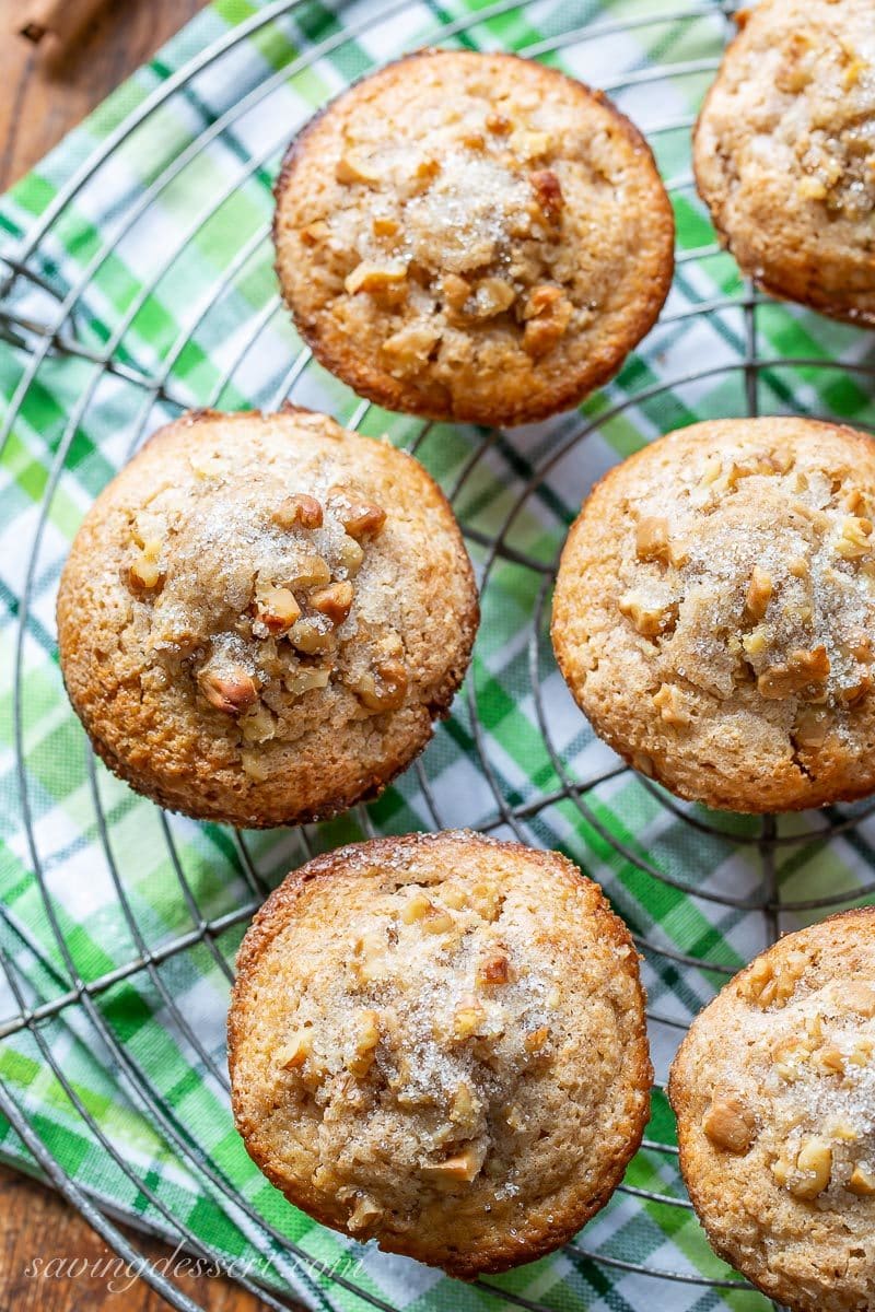 A cooling rack with cinnamon apple muffins topped with walnuts