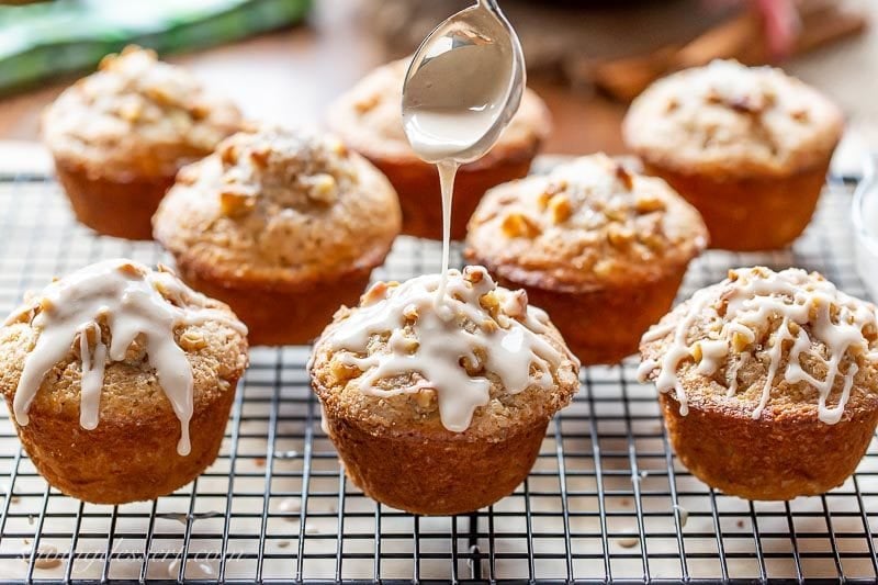 A cooling rack with cinnamon apple muffins drizzled with apple cider glaze