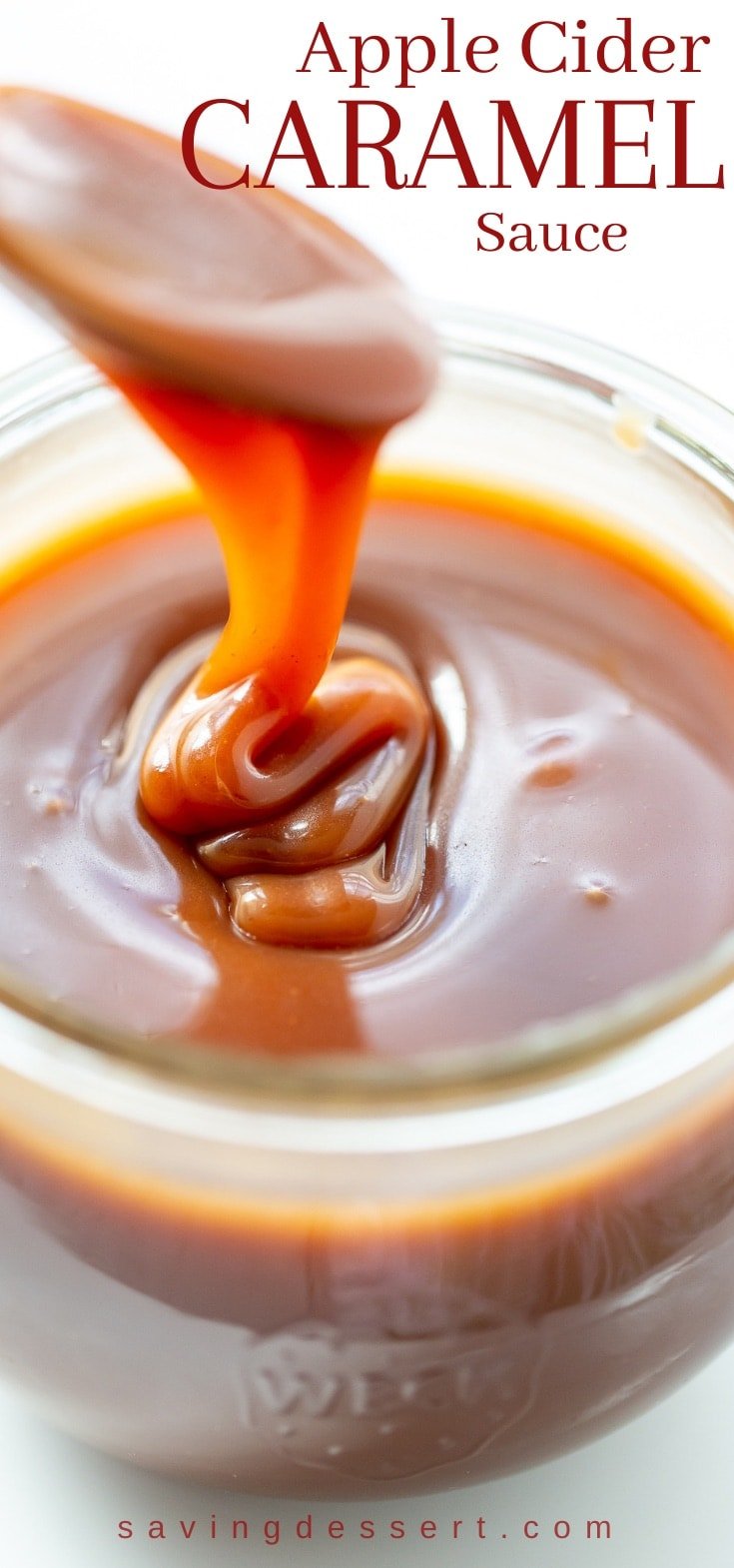 A spoonful of apple cider caramel sauce being drizzled into a jar