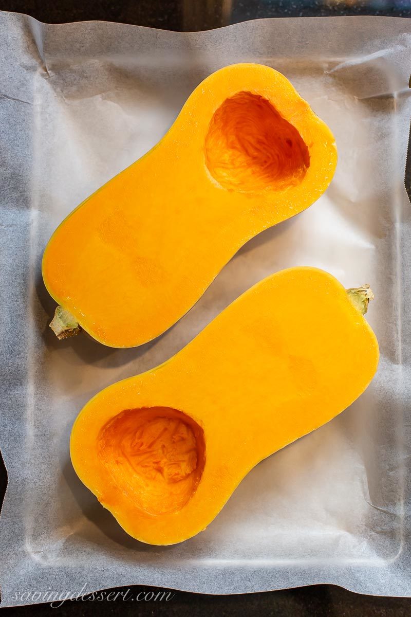 A sliced butternut squash on a baking pan with seeds removed 