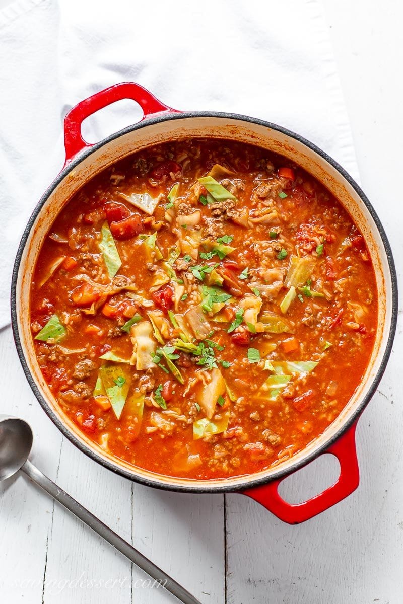 A pot of cabbage roll soup garnished with parsley