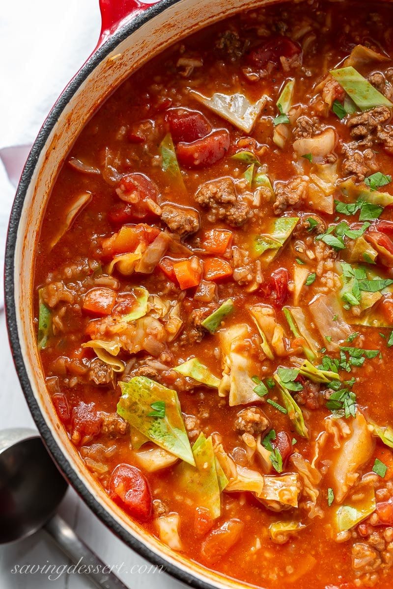 A close up of a pot of cabbage roll soup with carrots, tomatoes, rice and parsley