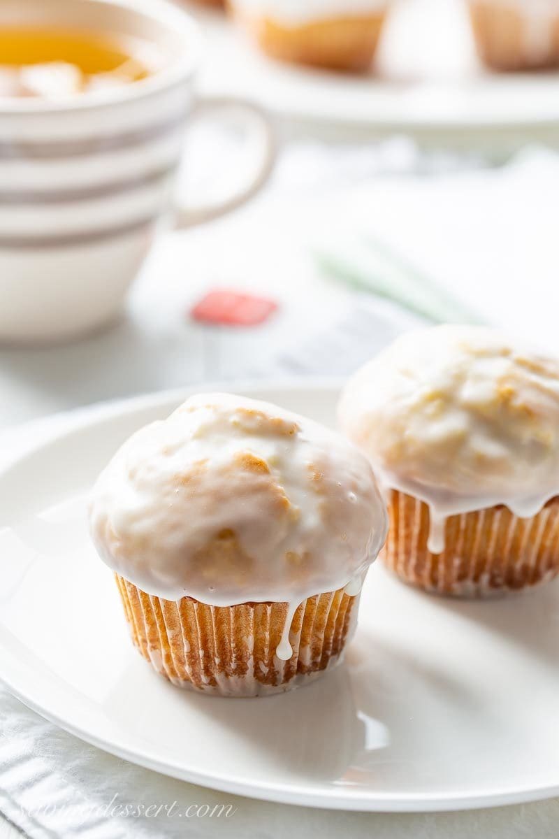 Iiced muffins on a plate with a cup of tea