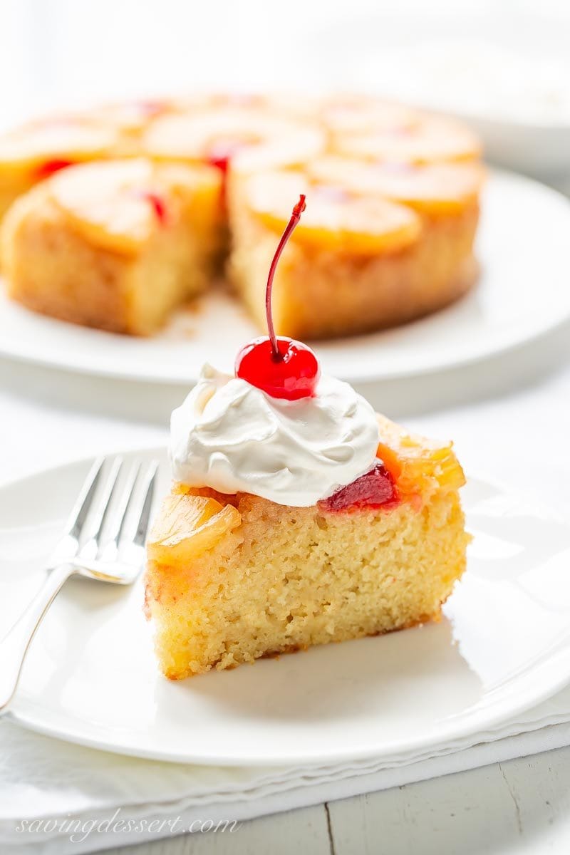 A slice of pineapple upside down cake with whipped cream and a cherry on top