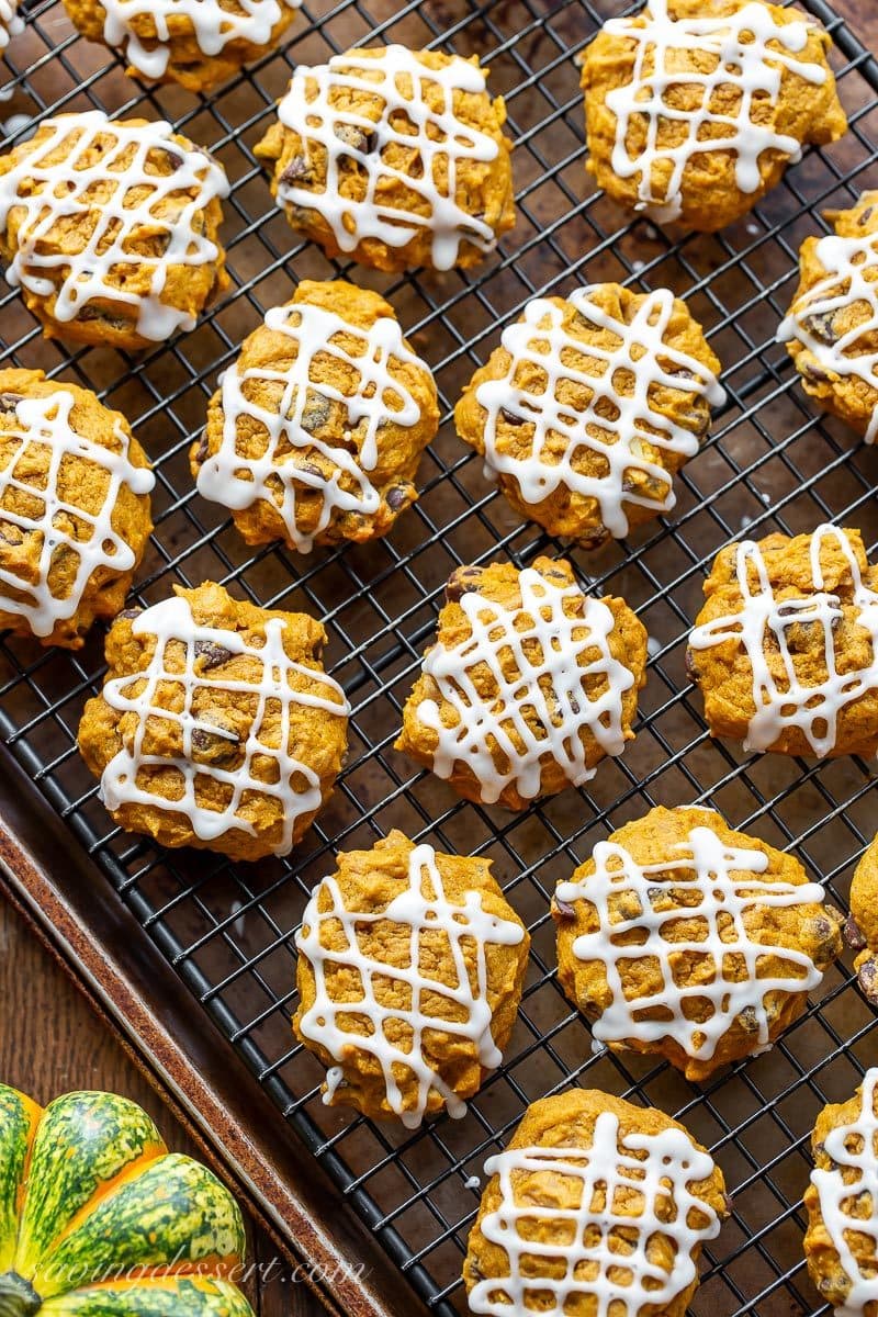 A cooling rack of pumpkin chocolate chip cookies drizzled with icing