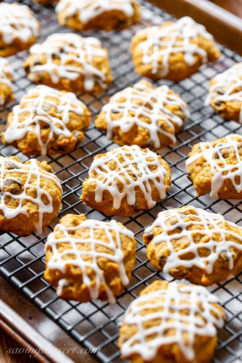 A cooling rack with pumpkin chocolate chip cookies drizzle with icing